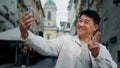 Joyful adult male tourist holding smartphone looking at screen taking pictures on webcam happy man blogger posing for Royalty Free Stock Photo