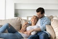 Joyful affectionate family couple relaxing on comfortable sofa.