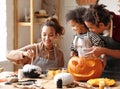 Joyful african american family mother, father and boy son enjoying Halloween preparation at home