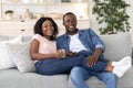 Joyful african family watching movie together at home, drinking coffee Royalty Free Stock Photo