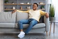 Joyful african american guy sitting on sofa at home Royalty Free Stock Photo