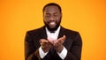 Joyful african-american male in formalwear holding piggybank, banking services