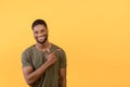 Joyful african american man pointing aside at copy space and smiling at camera, standing over yellow background Royalty Free Stock Photo