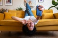 Joyful African American woman lying upside down on the sofa takes selfie with smart phone. Social media. Royalty Free Stock Photo