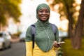 Joyful african islamic woman listening music outdoors with smartphone and earphones Royalty Free Stock Photo