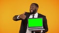 Joyful afro-american businessman showing prekeyed laptop and thumbs-up gesture