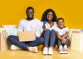 Joyful afro family with laptop, credit card and shopping bags. Royalty Free Stock Photo