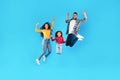 Joyful Arabic Family Jumping Shaking Fists Over Blue Background