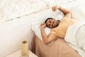 Joyful Arabic Man Awakening Stretching Arms Lying In Bedroom Indoors