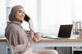 Joyful arabic secretary resting at workplace with cellphone and coffee