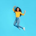 Joyful Arabic Woman Jumping Shaking Fists Over Blue Background, Square