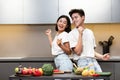 Joyful Asian Couple Dancing Preparing Dinner Having Fun In Kitchen Royalty Free Stock Photo