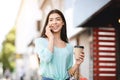 Joyful Asian Girl With Shopping Bags And Coffee Talking On Cellphone Outdoors Royalty Free Stock Photo