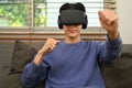 Joyful asian man experiencing opportunities of gaming in virtual reality headset. Futuristic technology concept