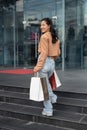 A joyful Asian woman is getting into a shopping mall, walking with her shopping bags Royalty Free Stock Photo