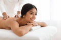 Joyful young indian woman getting body massage at spa Royalty Free Stock Photo