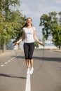 Athletic young woman training with a jumping rope on a park background. Gymnastics equipment concept. Royalty Free Stock Photo