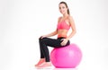 Joyful attractive young sportswoman sitting on pink fitball