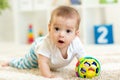 Joyful baby crawling on the floor in nursery room