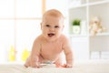 Joyful baby crawling on the floor in nursery room