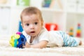 Joyful baby lying on the carpet in nursery room