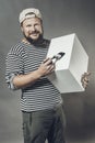 Joyful bearded craftsman with brush and blanc cube studio portrait