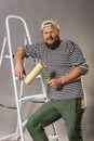 Joyful bearded craftsman with brush roller and ladder