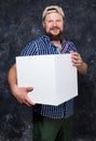 Joyful bearded man in shirt with blanc cube object for your logo
