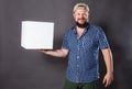 Joyful bearded man in shirt with blanc object looks like cube