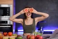 Funny and joyful young woman holding orange slices near her eyes and smiling. Royalty Free Stock Photo
