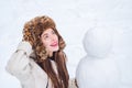 Joyful Beauty young woman Having Fun with snowman in Winter Park. Funny snowmen. Happy smiling girl make snowman on Royalty Free Stock Photo