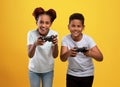 Joyful black brother and sister holding joysticks