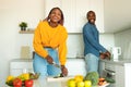 Joyful black couple cooking food and laughing, woman preparing salad for dinner, standing in modern kitchen Royalty Free Stock Photo