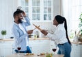 Joyful black couple having fun in kitchen, playfully fighting with kitchenware Royalty Free Stock Photo