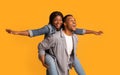 Joyful Black Couple Having Fun Together Over Yellow Background, Woman Piggybacking Boyfriend Royalty Free Stock Photo