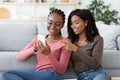 Joyful black girlfriends checking photos on mobile phone