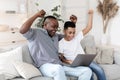 Joyful black granddad and grandson watching sports on laptop and emotionally cheering