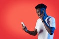 Joyful black guy listening to music online, using smartphone, earpods Royalty Free Stock Photo