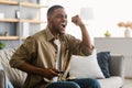 Joyful Black Guy Watching Sports Game On TV Shouting Indoors