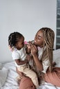 Joyful black happy woman applying makeup on her daughter& x27;s face Royalty Free Stock Photo