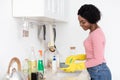 Joyful black lady washing dishes, copy space