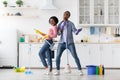Joyful black couple singing songs while cleaning kitchen, copy space