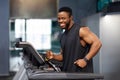 Joyful black man in sportswear running at gym