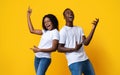 Joyful black man and woman dancing and singing on yellow