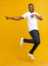 Joyful millennial guy jumping on air and pointing aside Royalty Free Stock Photo