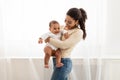 Joyful Black Mommy Carrying Baby In Arms Standing At Home