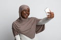 Joyful Black Muslim Lady In Hijab Taking Selfie On Smartphone