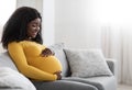 Joyful black pregnant woman hugging her big tummy Royalty Free Stock Photo