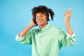 Joyful black teen guy listening to music in headphones, closing eyes and relaxing over blue studio background Royalty Free Stock Photo