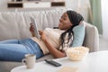 Joyful black woman watching movie, using mobile application on pad Royalty Free Stock Photo